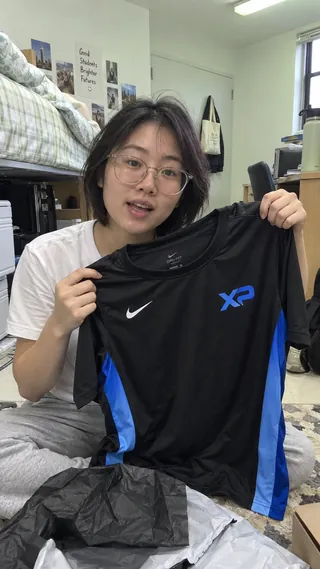 Ambassador content mockup of a student unpacking an XtraPoint jersey in a dorm room.